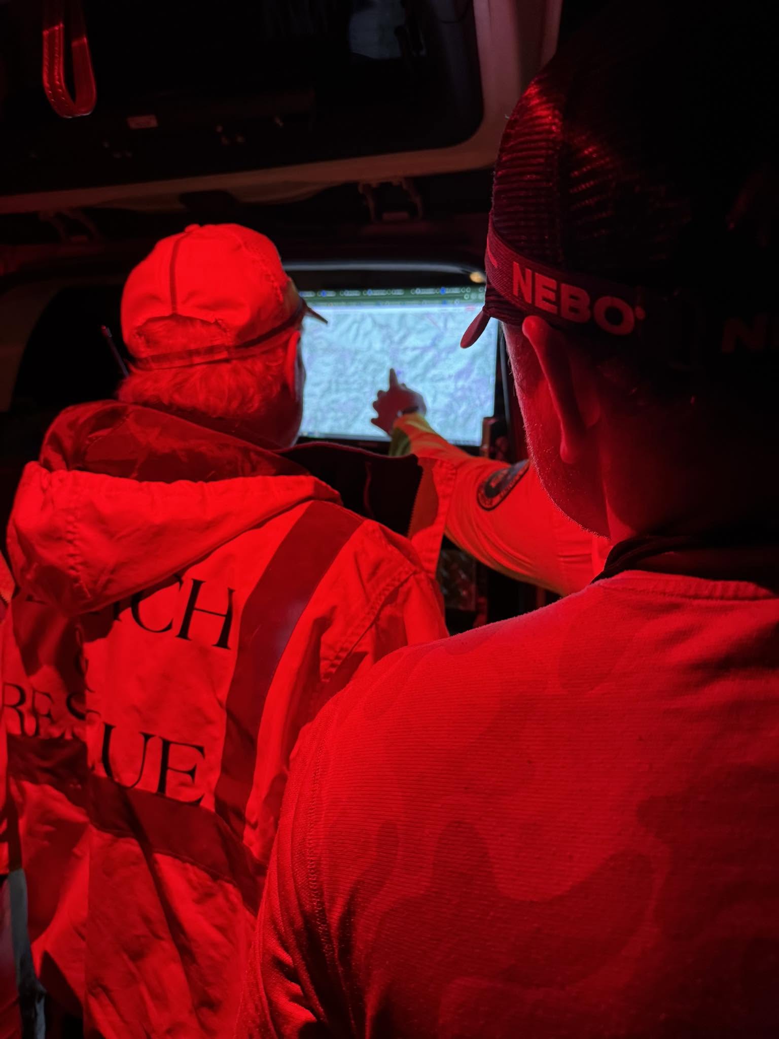 An image of SAR members looking at a map at night.